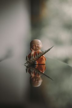 a small figurine sitting on top of a glass table next to a plant