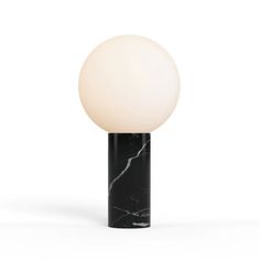 a black and white table lamp with a marble ball on it's base, against a white background