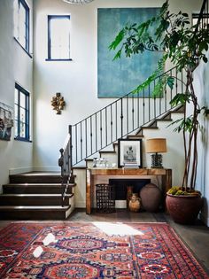 a staircase in a house with potted plants and pictures on the wall next to it