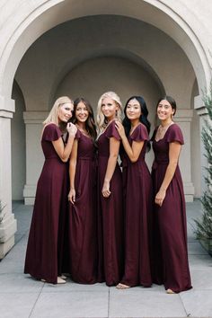 the bridesmaids are posing for a photo in front of an archway with greenery