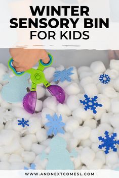 a person is playing with snowballs in a bin filled with white balls and blue snowflakes