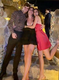 three people posing for the camera in front of some rocks and stairs with their arms around each other