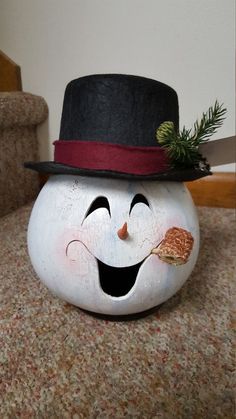 a white pumpkin with a black top hat on it's head and a spoon in its mouth