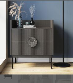 a grey cabinet with two vases on top and a black lamp next to it