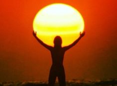 a person standing on the beach with their arms in the air as the sun sets