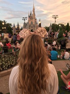 the back of a woman's head in front of a castle at disneyland world