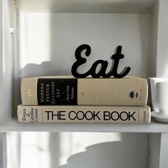 two books are stacked on top of each other with the word eat spelled in cursive letters