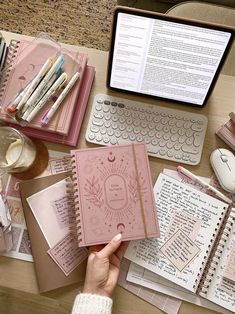 a person is holding a notebook in front of a laptop and several other items on a desk