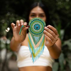 a woman holding up a piece of beaded art with her hands and eyes closed