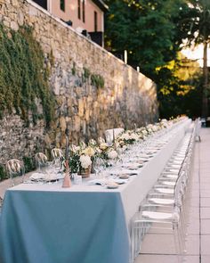 a long table is set up outside for an outdoor dinner party with white and blue linens