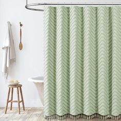 a green shower curtain in a bathroom next to a white bathtub and wooden stool