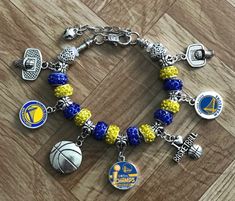 a charm bracelet with charms and basketballs is on a wooden floor, next to a pair of shoes