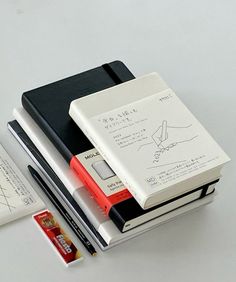 several notebooks and pens are stacked on top of each other