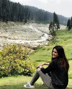 a woman sitting on top of a lush green hillside