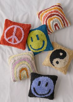 four pillows with smiley faces on them and one has a peace sign in the middle