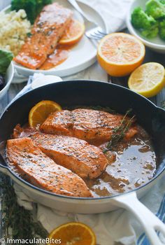 salmon and oranges are in a pan on a table with other foods around it