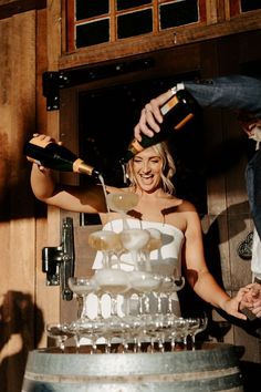 a man and woman are pouring champagne into a cake