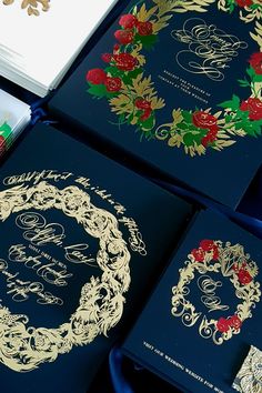 four blue wedding cards with gold and red roses on them, sitting next to each other