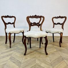 three chairs sitting on top of a wooden floor