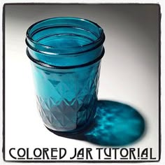 a blue jar sitting on top of a white table next to a shadow that reads colored jar