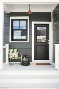 the front door of a house with a green chair on the porch next to it