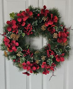 a christmas wreath with holly and poinsettis hangs on the front door,