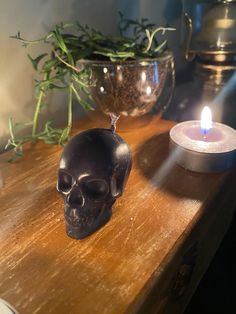 a black skull sitting on top of a wooden table next to a candle