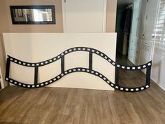 a white wall with black and white film strip design on it's sides, next to a wooden floor