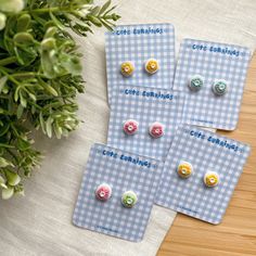 three pairs of button earrings sitting on top of a table next to a potted plant