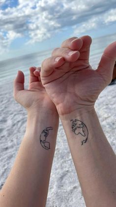 two people holding their hands up to each other with small tattoos on the wrist and arm