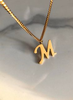 Letter M necklace, set on a stainless steel ,golden color chain. Chain length 19'  With addition cost there is an option to add a white freshwater pearl, as a charm, next to the letter. 6 mm, white round pearl Kindly choose your option. Beautiful spiritual gift. Please make sure you to pay attention to the size of the pendant. I have added pictures next to 25 cent coin, and measurement tape.  Need a different length just write it to me in the "message to the seller" box of the order form. **LIMI Gold Initial Necklace In Stainless Steel, Stainless Steel Initials Name Necklace, Gold Stainless Steel Initial Necklace, Minimalist Stainless Steel Name Necklace, Dainty Tan Initial Necklace For Gift, Minimalist Personalized Tan Charm Necklaces, Gold Dainty Stainless Steel Name Necklace, Dainty Gold Stainless Steel Name Necklace, Minimalist Gold Stainless Steel Name Necklace