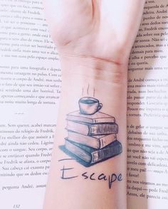 a person with a tattoo on their wrist holding a stack of books and a cup of coffee