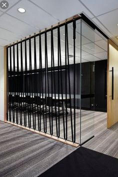 an office with glass partitions and black chairs in the middle, along with carpeted flooring