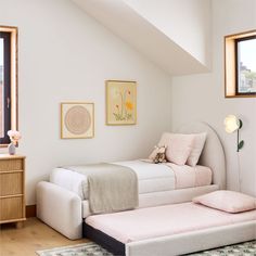 two twin beds in a bedroom with pink and white bedding, artwork on the wall