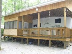 a large wooden deck with a camper on it's side in the woods