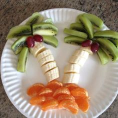 a white paper plate topped with cut up fruits and veggies in the shape of palm trees