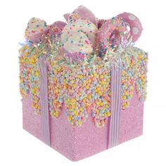 a pink gift box filled with lots of sprinkles and candy covered balls