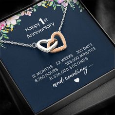 a necklace with two intertwined hearts on it in a gift box that says happy 1st anniversary