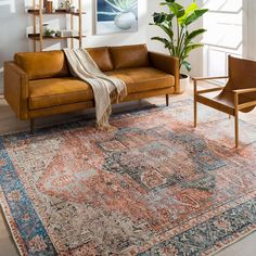 a living room with a couch, chair and rug on the floor in front of a window