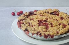 a pie sitting on top of a white plate with cherries next to the pie