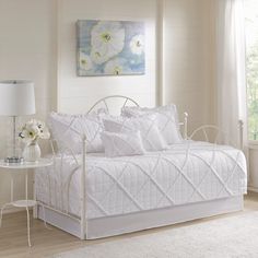 a white daybed in a bedroom next to a window with flowers on the bed