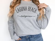 a woman wearing a gray laguna beach california sweatshirt