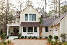 a white house with two garages and lots of trees in front of the house