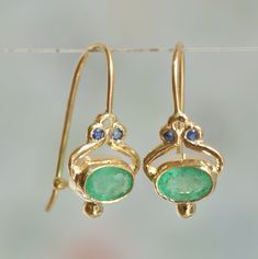 "These dangle Green Emerald earrings are made of 14k solid yellow gold with small blue Sapphires. The earrings are handmade by me. If you love earrings that are not exactly identical - these are the earrings for you. The Green Emerald stones are a slightly different one from the other. I am making my best to find two identical natural Emerald. If you love green and blue together - these earrings are perfect for you! This Blue Sapphire, Green Emerald, and 14k gold combination add color to everyda Emerald Earring, Sapphire Earring, Handmade Gold Ring, Emerald Green Earrings, Medieval Jewelry, Emerald Earrings, Gold Earring, Sapphire Earrings, Drop Earring