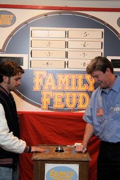 two men standing next to each other in front of a table with a clock on it