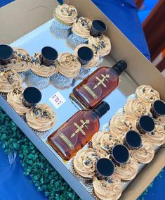 cupcakes and bottles of whiskey sit in a box on a blue tablecloth