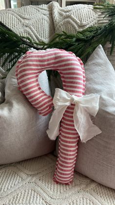 a decorative pillow with a bow on it sitting on a couch next to a christmas tree