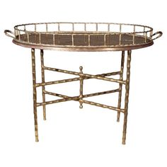 a round tray with metal handles and bamboo trimmings on the bottom, sitting on a stand