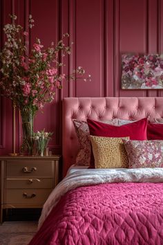 a bedroom with pink walls and red bedspread, flowers in vases on the nightstand