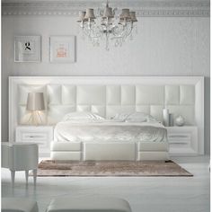 a white bedroom with chandelier, bed and nightstands on the side wall